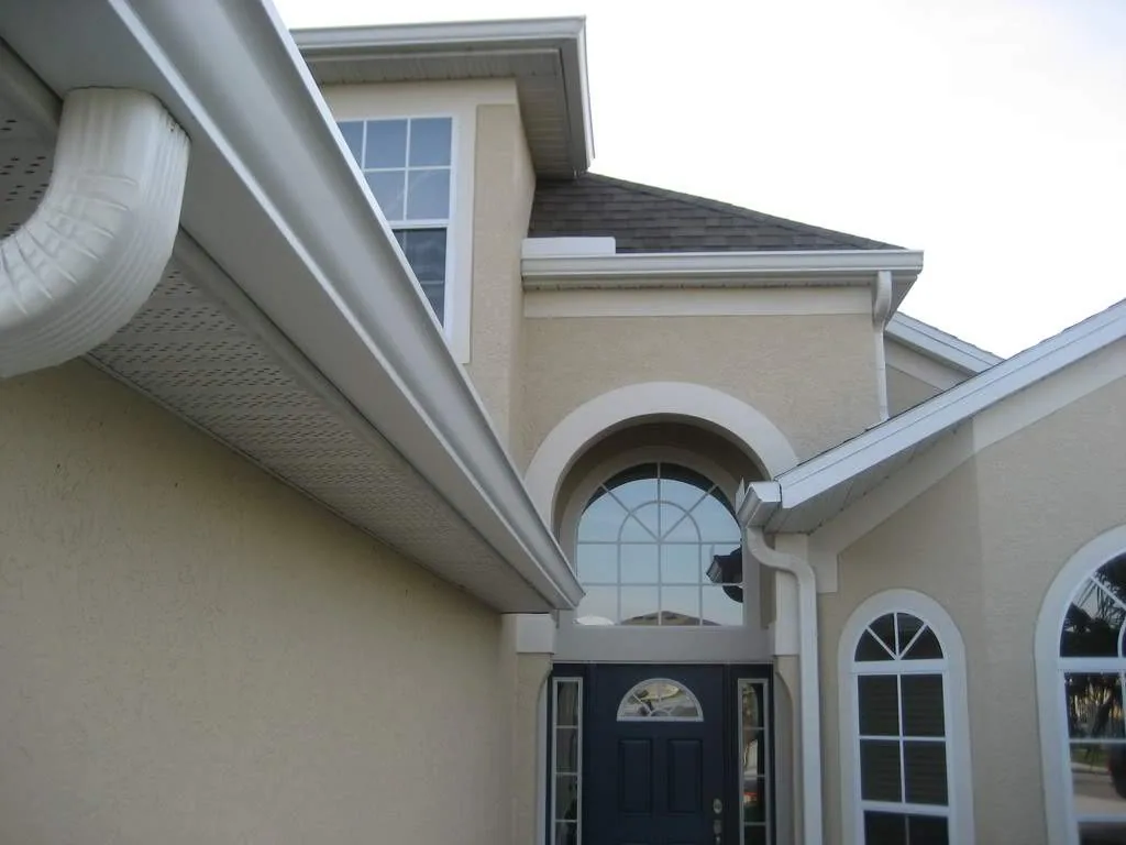 White k style gutter downspout elbow tan stucco arched entry, Sanford